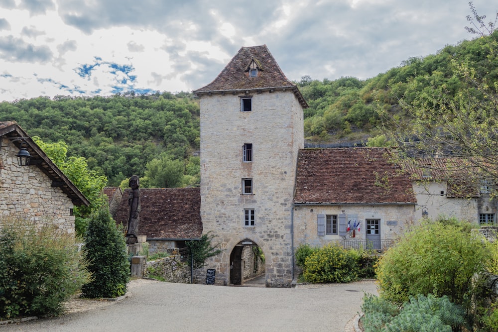 a stone building with a tower in the middle of a road