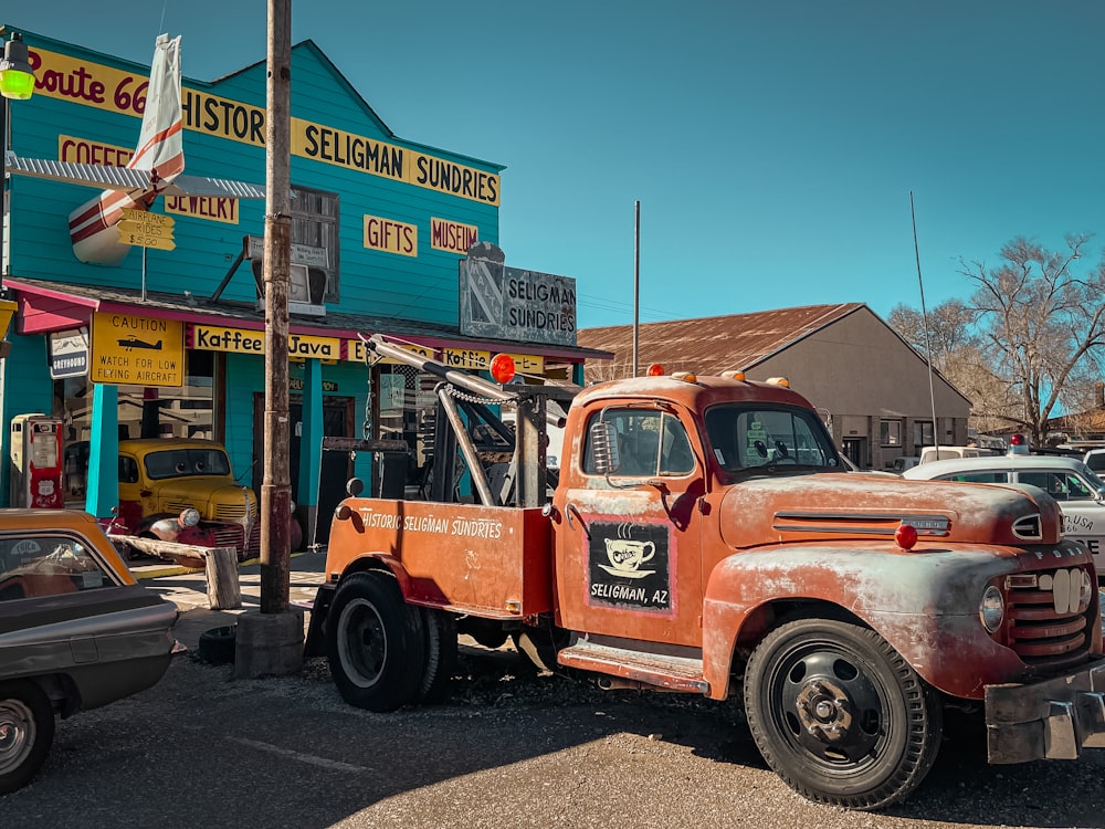 an old orange tow truck parked in front of a store