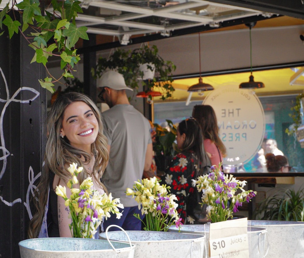 a woman standing next to two buckets of flowers