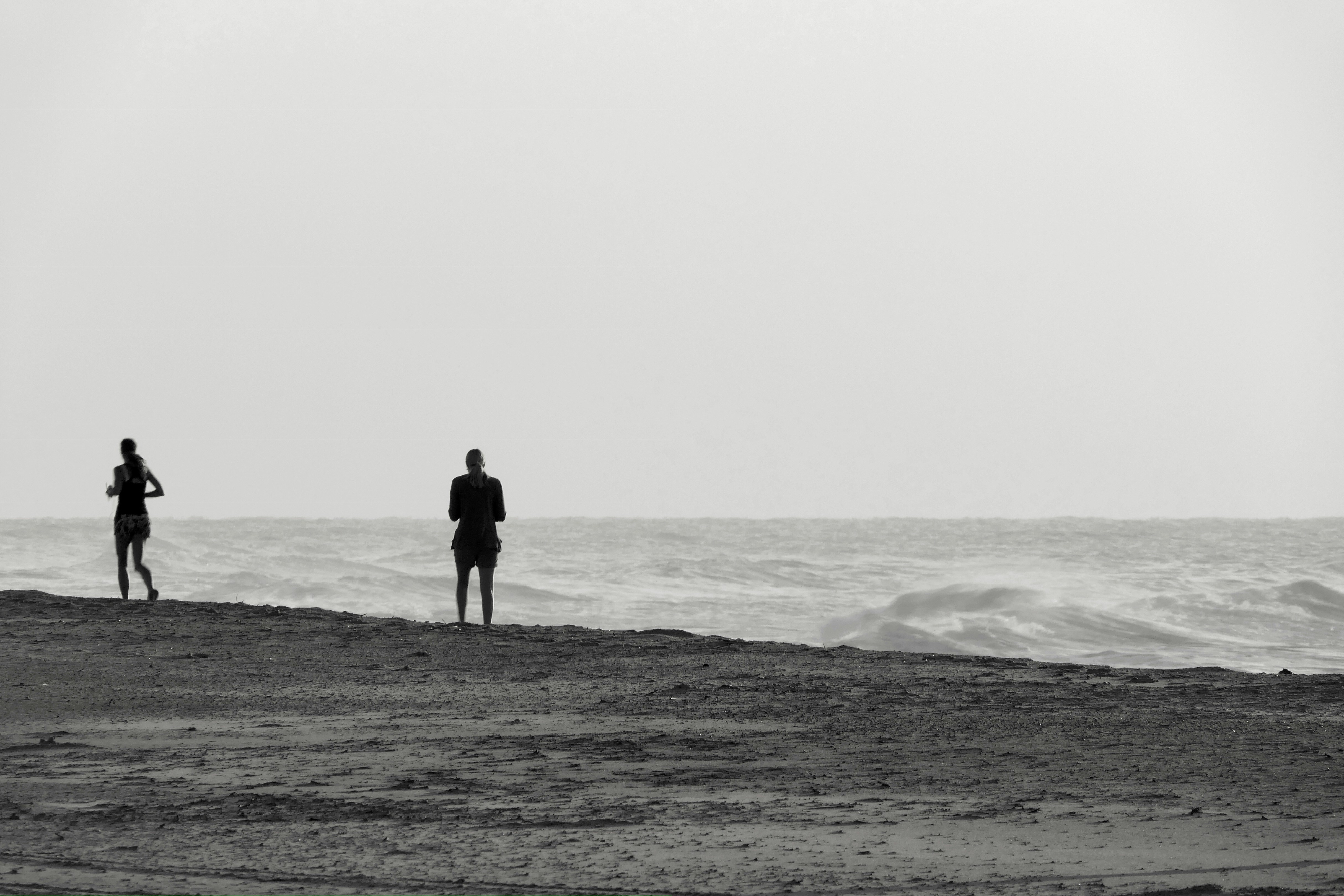 a couple of people standing on top of a sandy beach