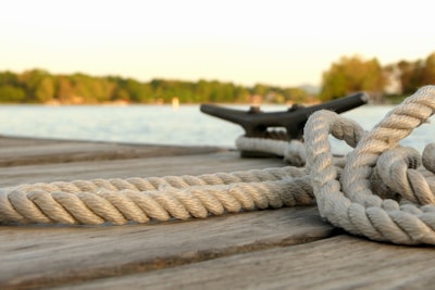 Close-up of light blue nautical ropes neatly coiled on a wooden dock.