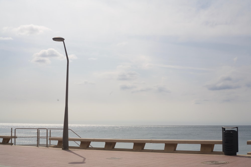 a street light next to the ocean on a cloudy day