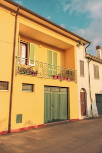 a yellow building with green shutters and a balcony