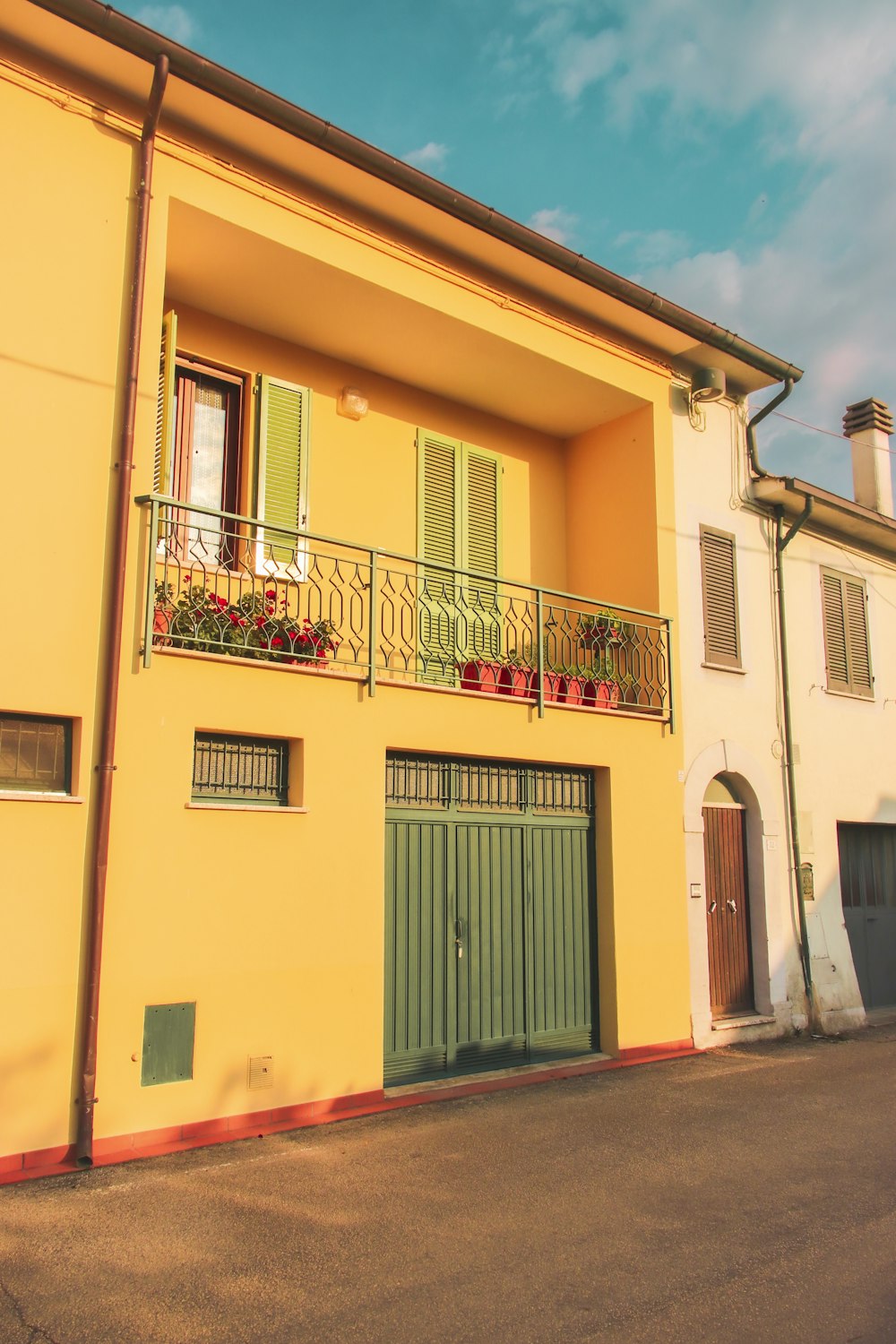 a yellow building with green shutters and a balcony