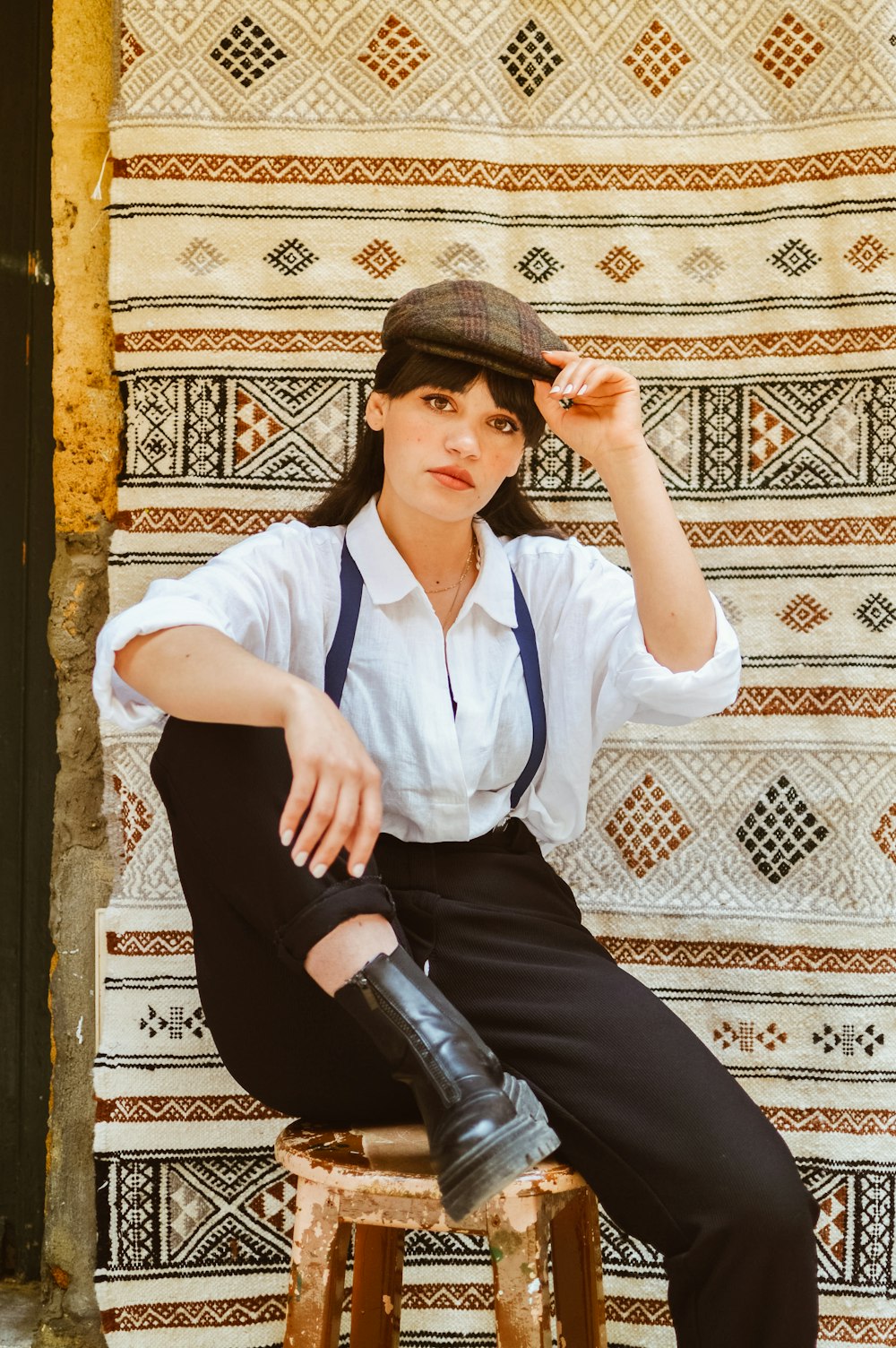 a woman sitting on a stool wearing a hat