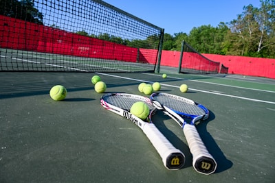 A vibrant tennis court under bright sunlight with players mid-match, rackets swinging.