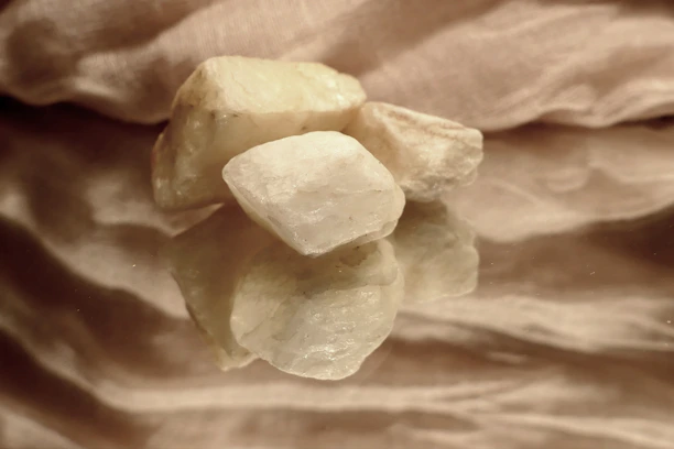 A close-up of smooth, hand-painted diffuser stones arranged on a wooden tray with soft natural light.