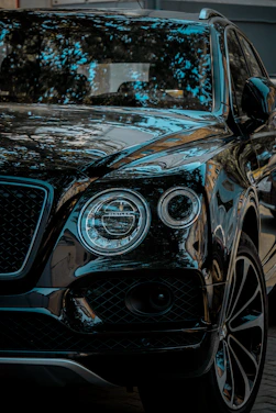 A sleek black luxury SUV gleaming under showroom lights with gold and red accents highlighting its curves.