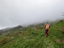 Hiker wearing a hypershell exoskeleton walking through a lush green valley.
