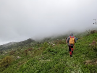 A hiker wearing a lightweight, waterproof jacket trekking through a misty mountain trail.