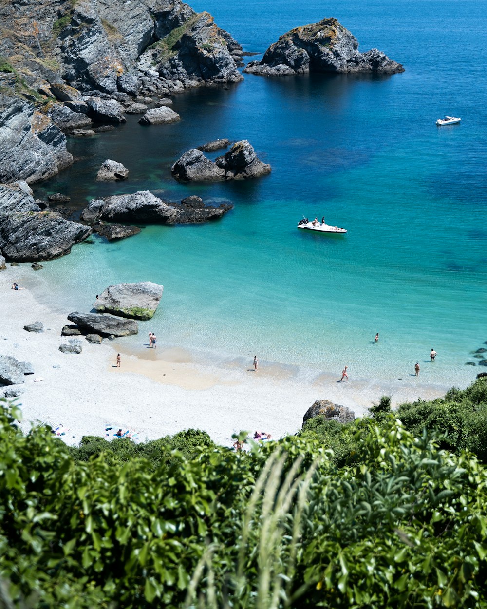 a group of people on a beach with a boat in the water