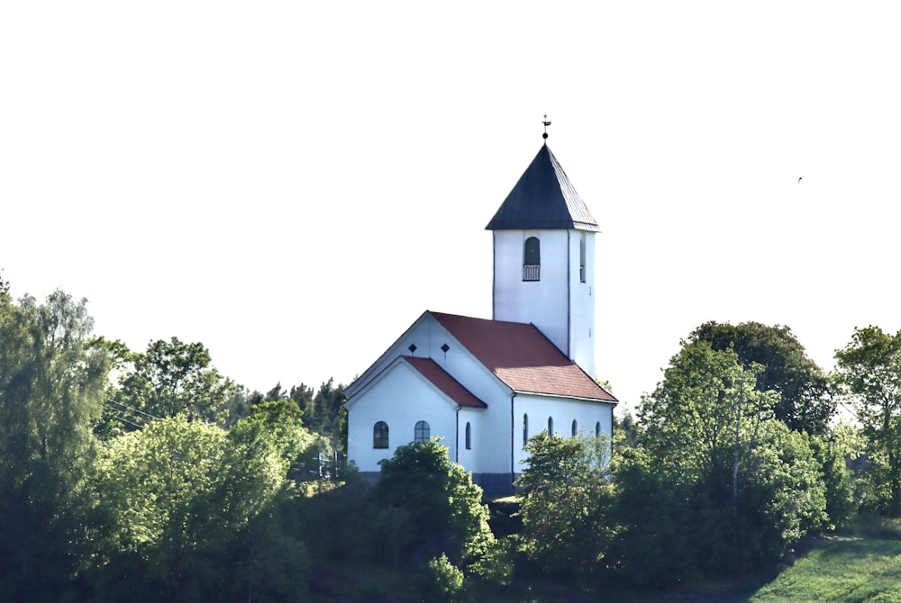Una iglesia blanca con un techo rojo rodeado de árboles