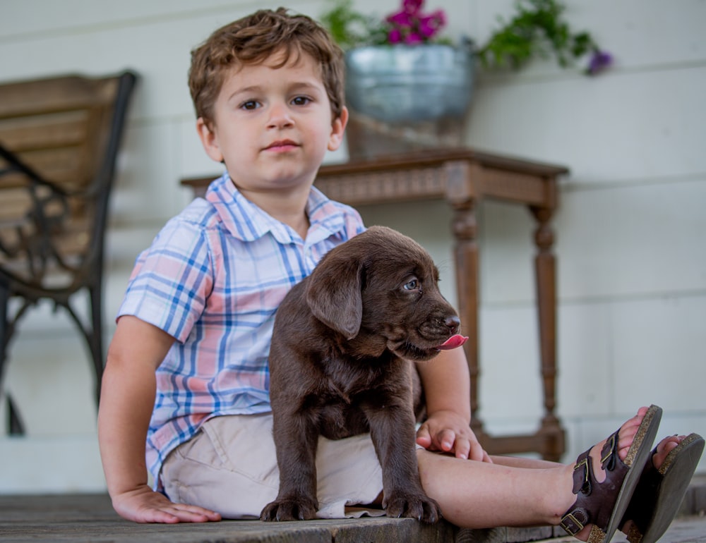 a young boy sitting on a porch with a puppy