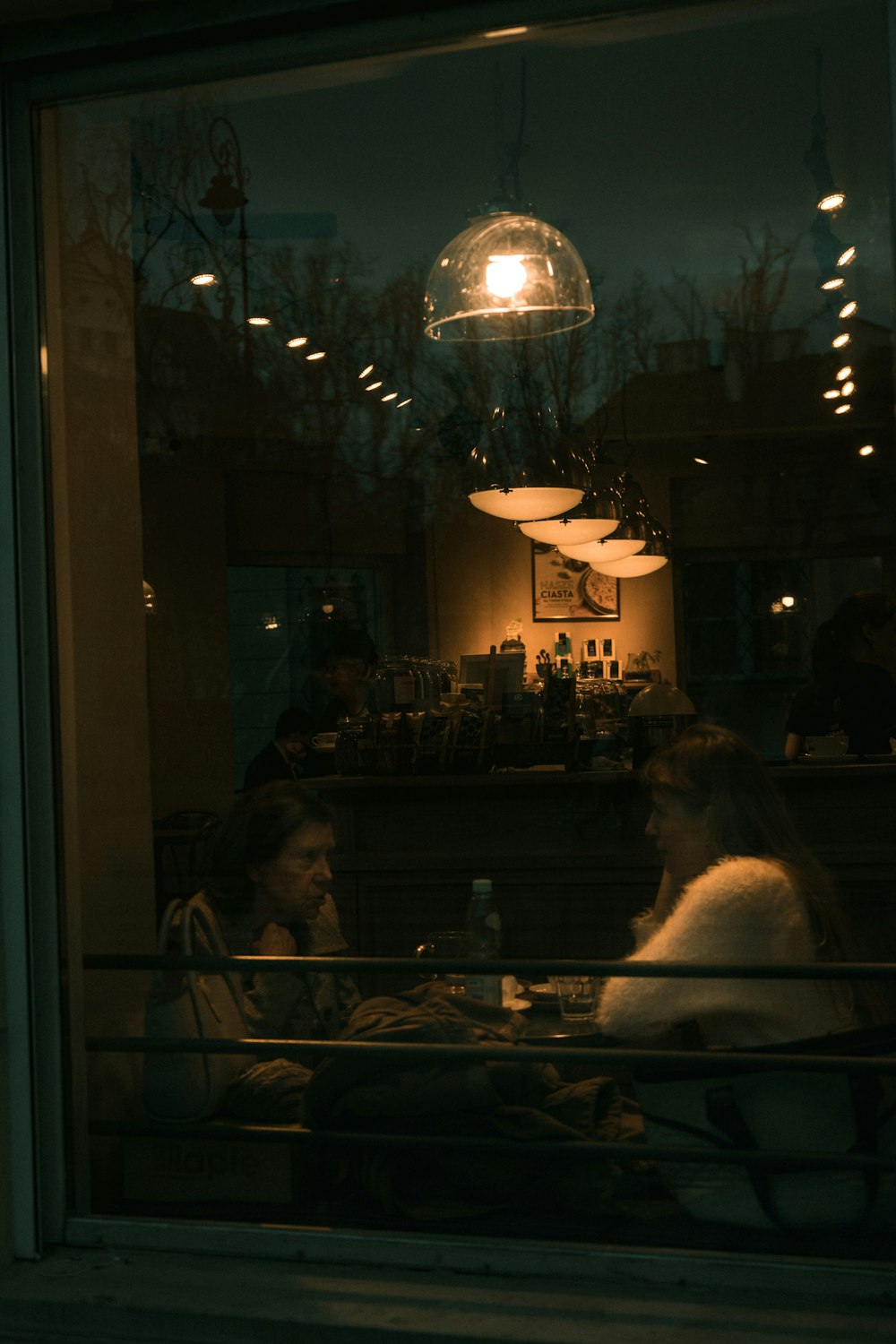 a couple of women sitting at a table in front of a window