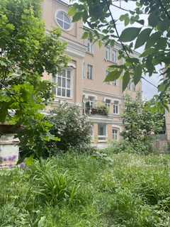 Modern residential building with soft pastel tones and landscaped gardens in the foreground