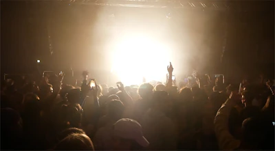 Close-up of excited faces enjoying a live show in a black-themed venue.