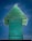 A large, green, translucent glass sculpture shaped like an upward-pointing arrow stands against a vivid blue sky. The layered texture of the glass creates a three-dimensional effect with subtle variations in color and transparency.