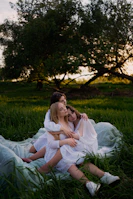 A group of women embracing during a retreat, surrounded by nature and soft morning light.