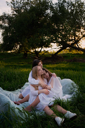 A group of women embracing during a retreat, surrounded by nature and soft morning light.