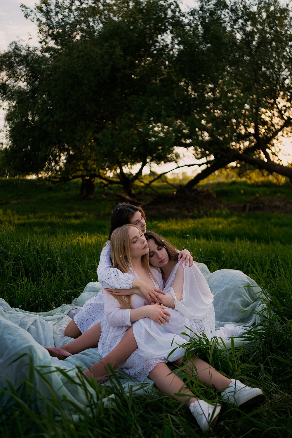 two women sitting on a blanket in the grass