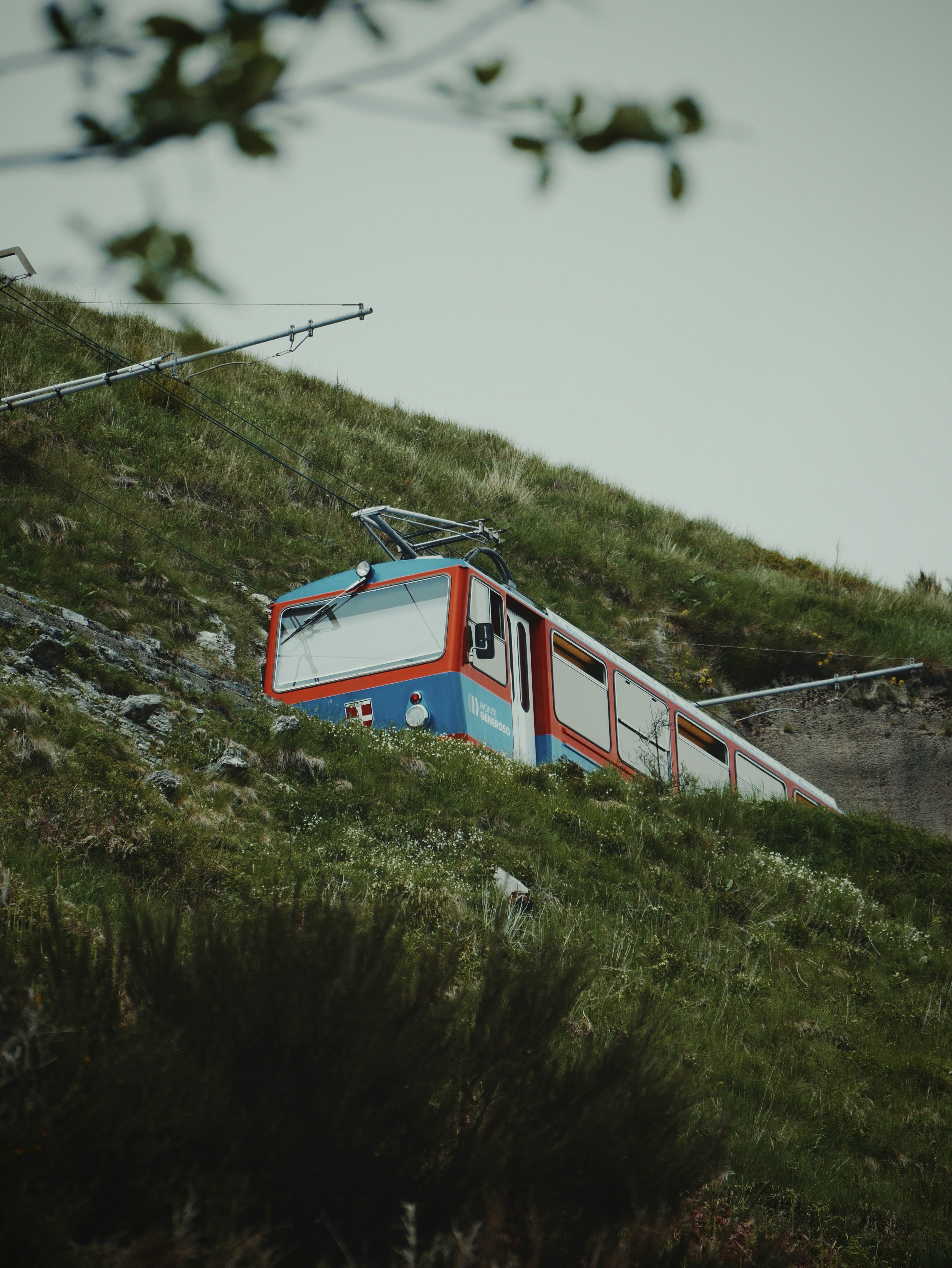 ein rot-weiß-blauer Zug, der einen Hügel hinunterfährt