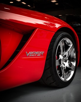 Close-up of a sleek Dodge Viper's aggressive front grille and headlight under bright sunlight.