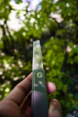 Hands gripping a sleek, ergonomic cutting tool against a backdrop of lush jungle foliage.