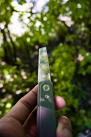 Hands holding a sharp hunting knife outdoors with a forest background