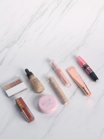 Futuristic makeup products arranged on a reflective black surface with golden highlights.