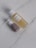 Two cosmetic bottles are placed on a light marble surface. One is a transparent bottle filled with a yellow liquid and has a white cap, labeled as botanical calendula oil. The other is a smaller pump bottle with a brown base and white top.