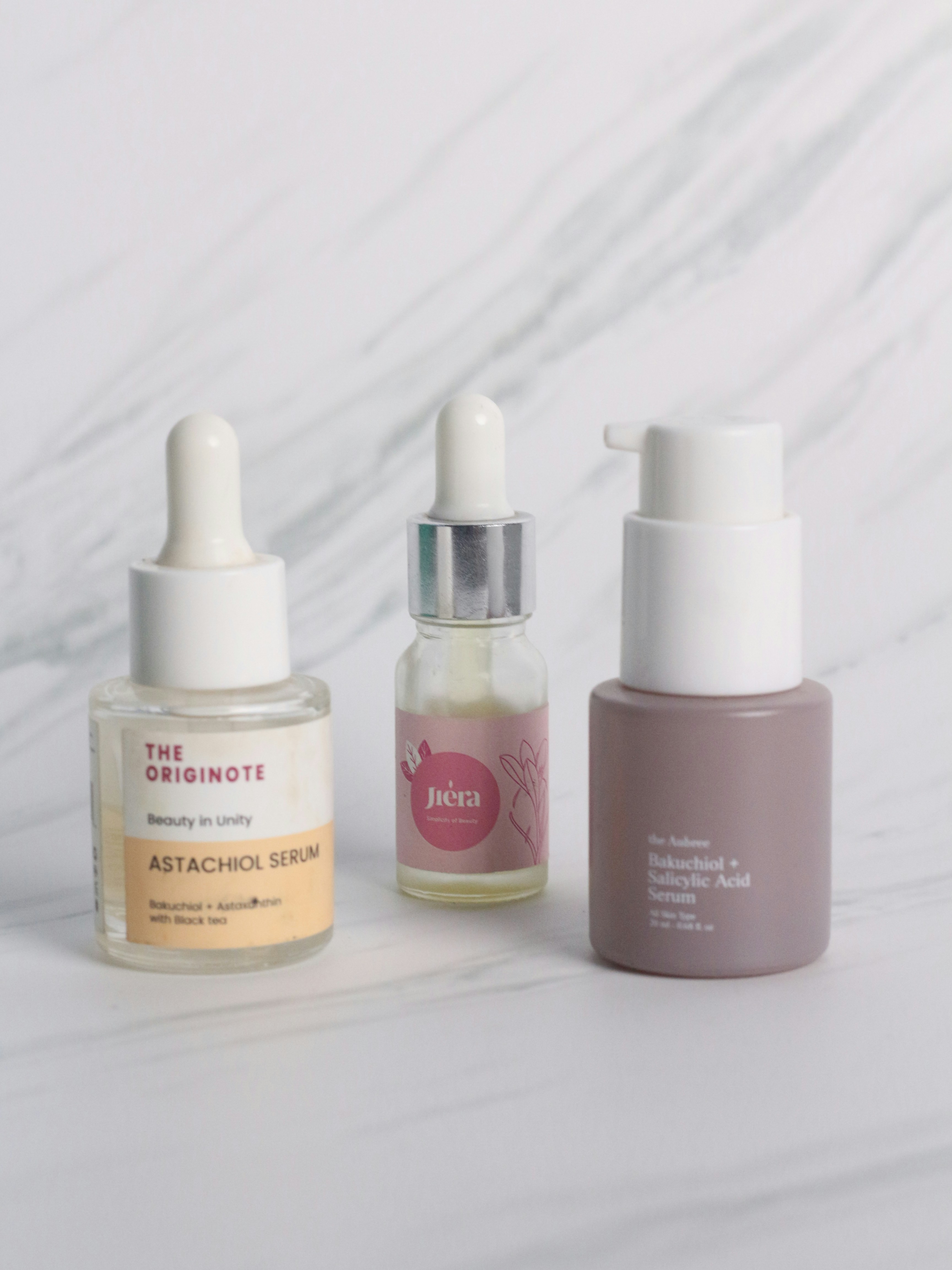 Luxury eye serum vial with crystal dropper on white marble background editorial beauty