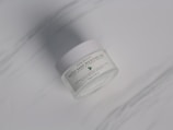 A white jar labeled 'Water Bank Moisture Gel' with a subtle green leaf graphic is placed on a smooth, light gray surface.