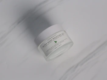 Elegant glass jar of Hydravince moisturizer with soft green hues and natural light.