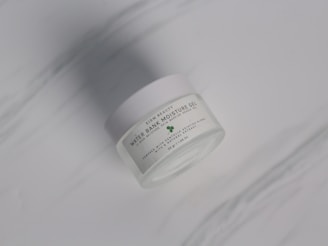 A white jar labeled 'Water Bank Moisture Gel' with a subtle green leaf graphic is placed on a smooth, light gray surface.