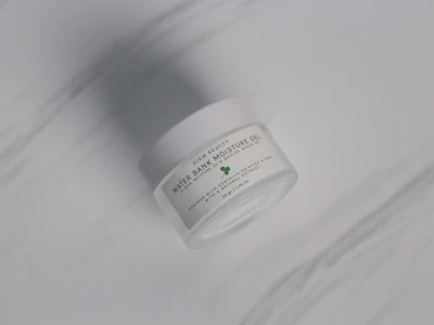 Elegant Hydravince moisturizer jar with subtle reflections on a smooth beige surface.