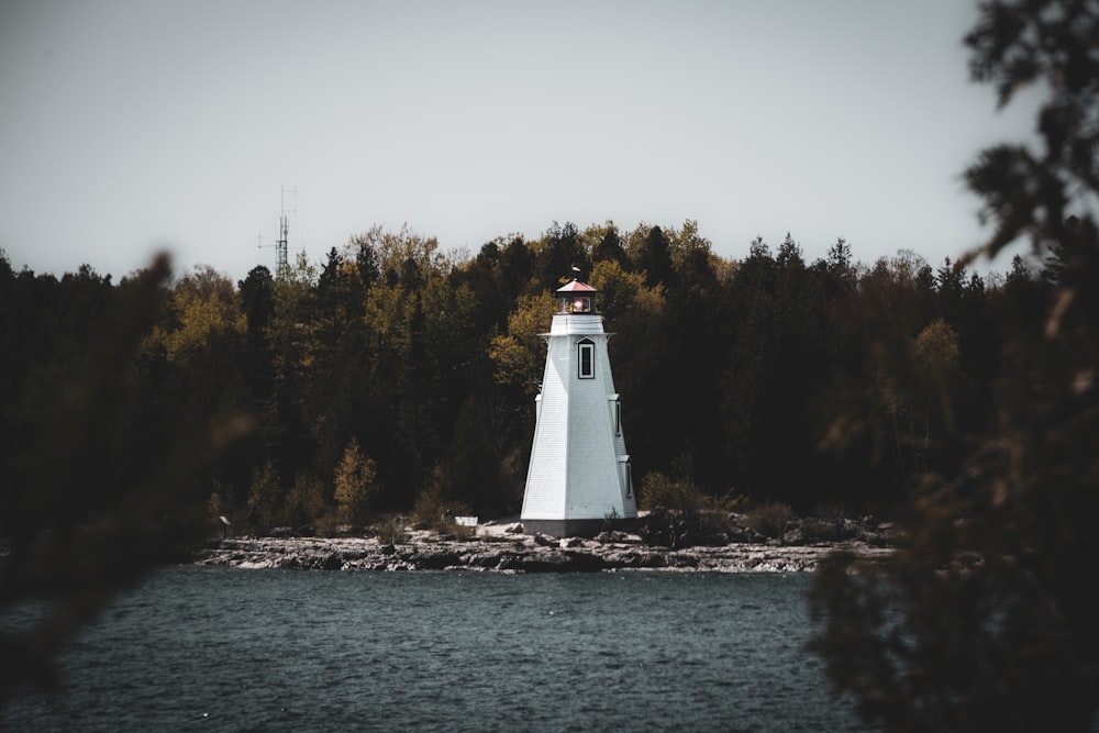 a white light house sitting on top of a body of water