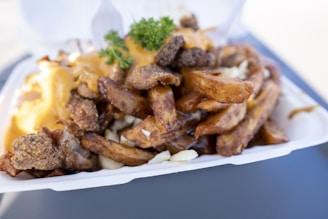 A hearty poutine topped with cheese curds and rich gravy in a rustic bowl.