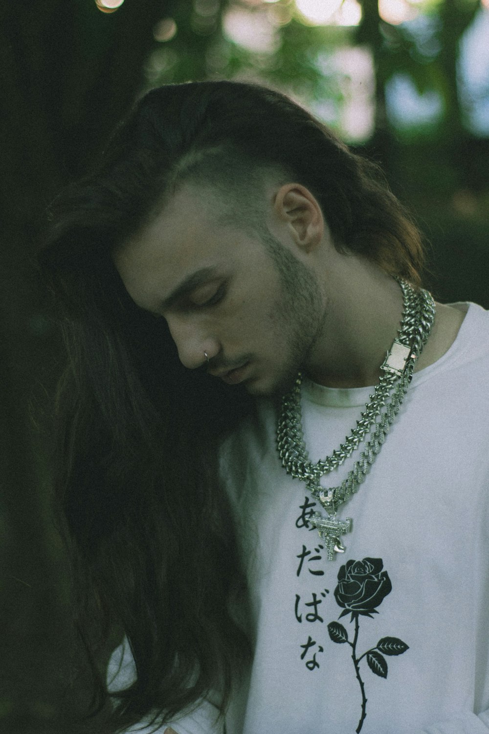 Un uomo con i capelli lunghi che indossa una camicia bianca