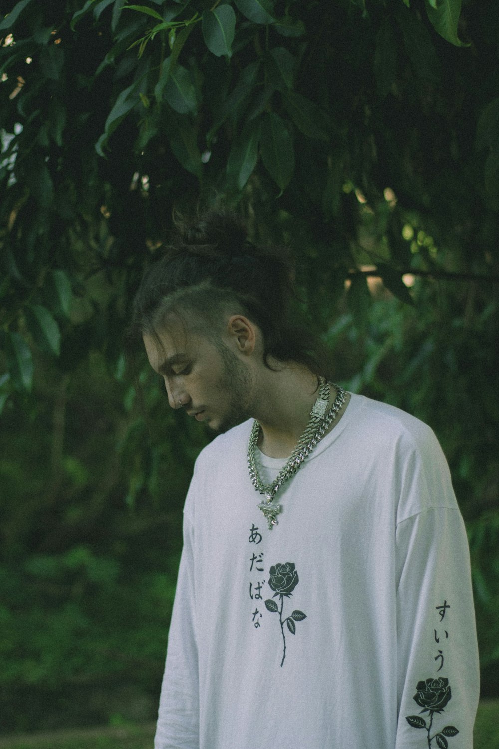 a man standing under a tree wearing a necklace