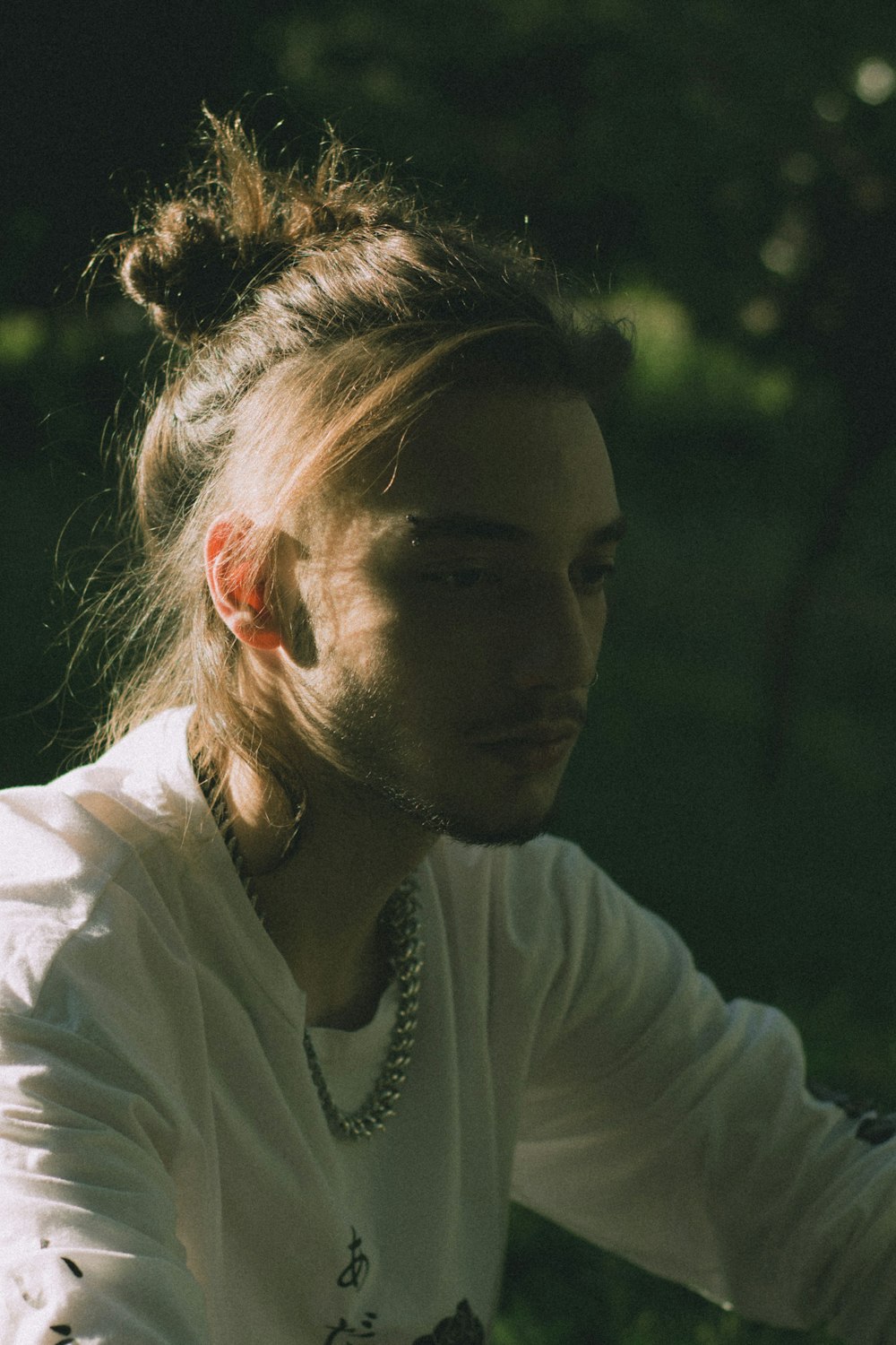 a woman sitting in the grass with her hair in a bun