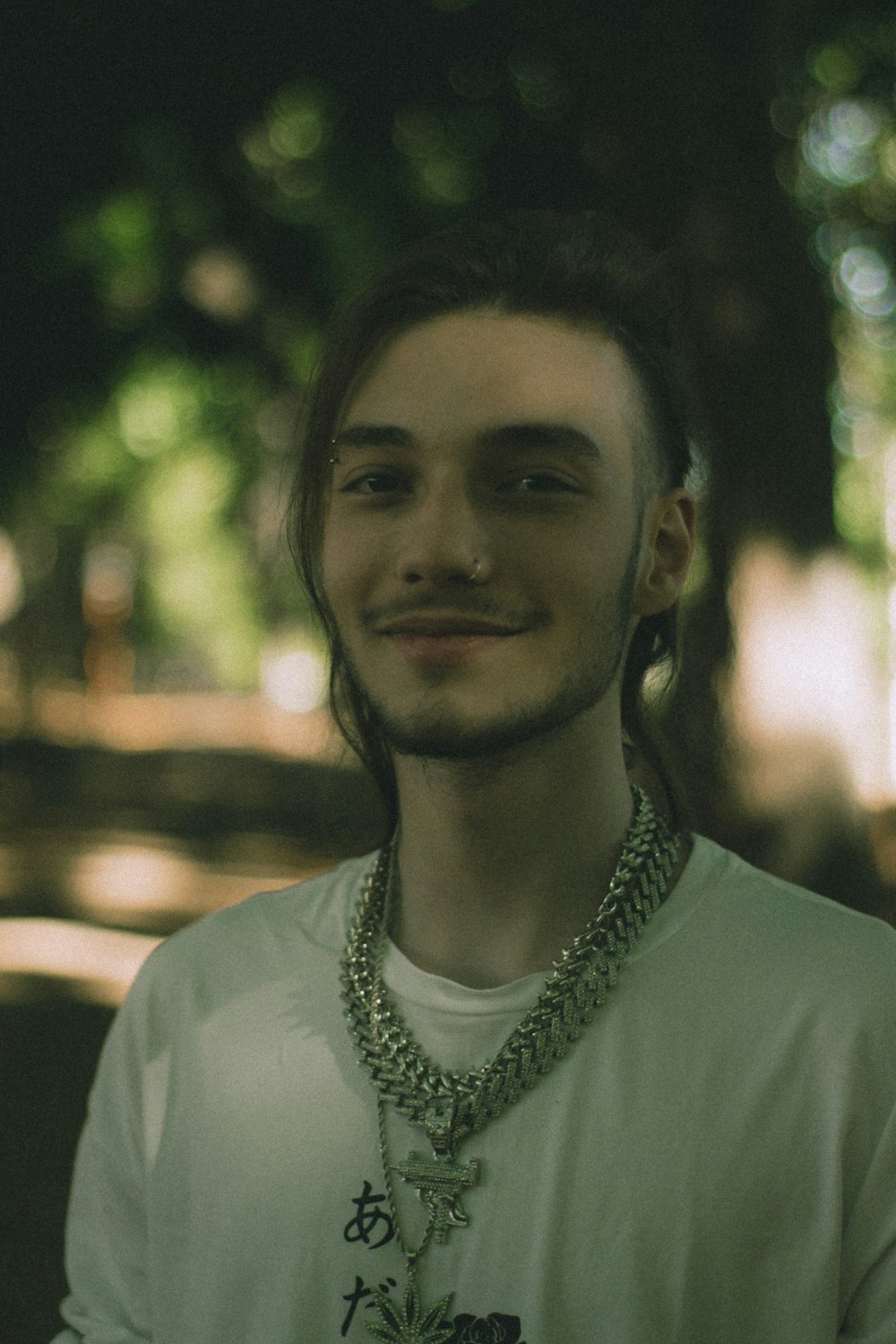 a man wearing a necklace and a white shirt