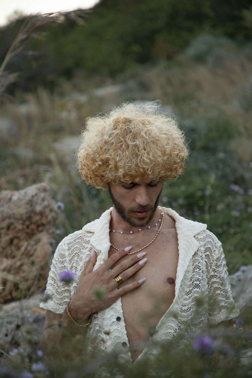 a shirtless man standing in a field of flowers