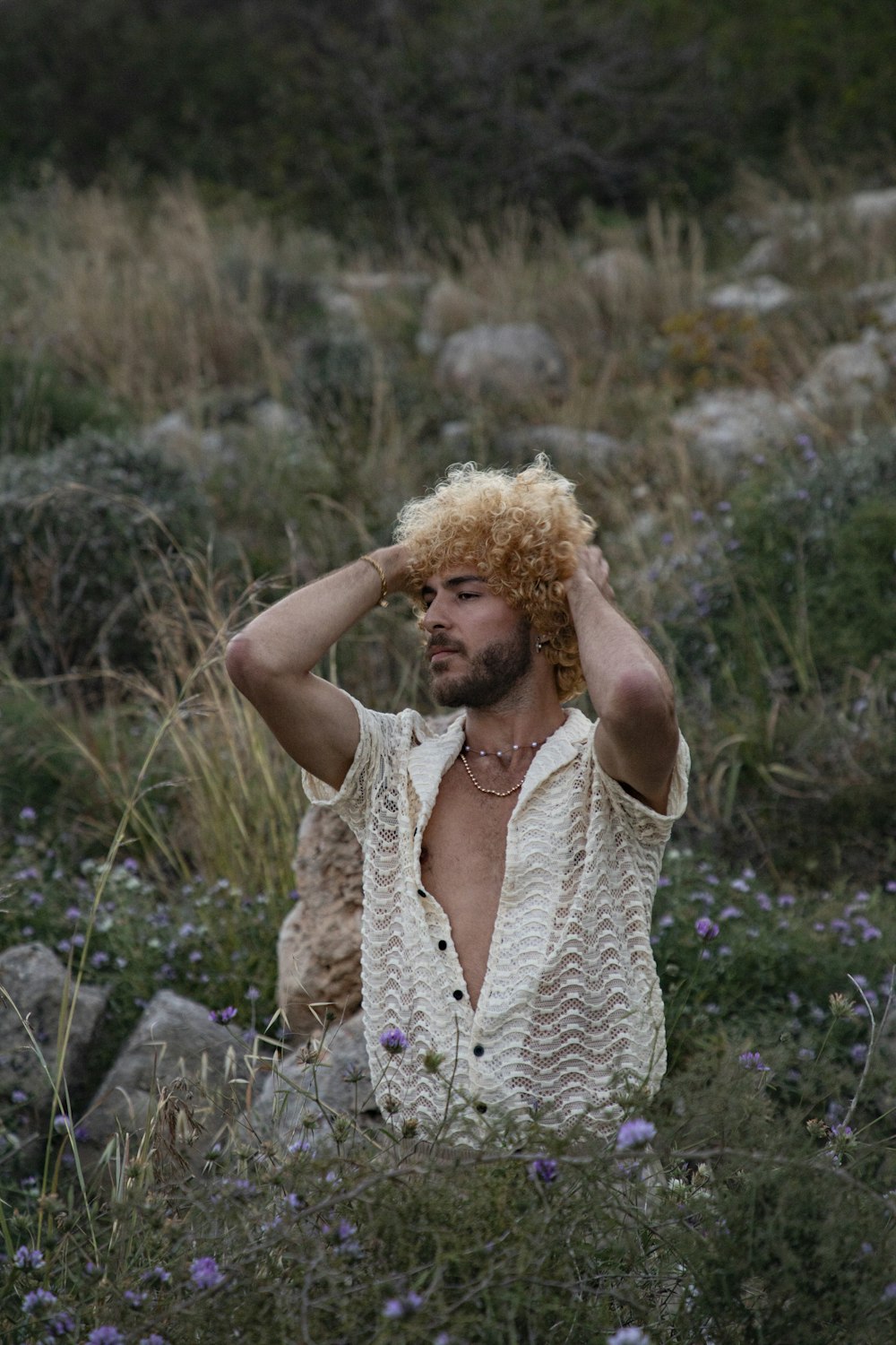 a man in a field of wildflowers with his hair blowing in the wind