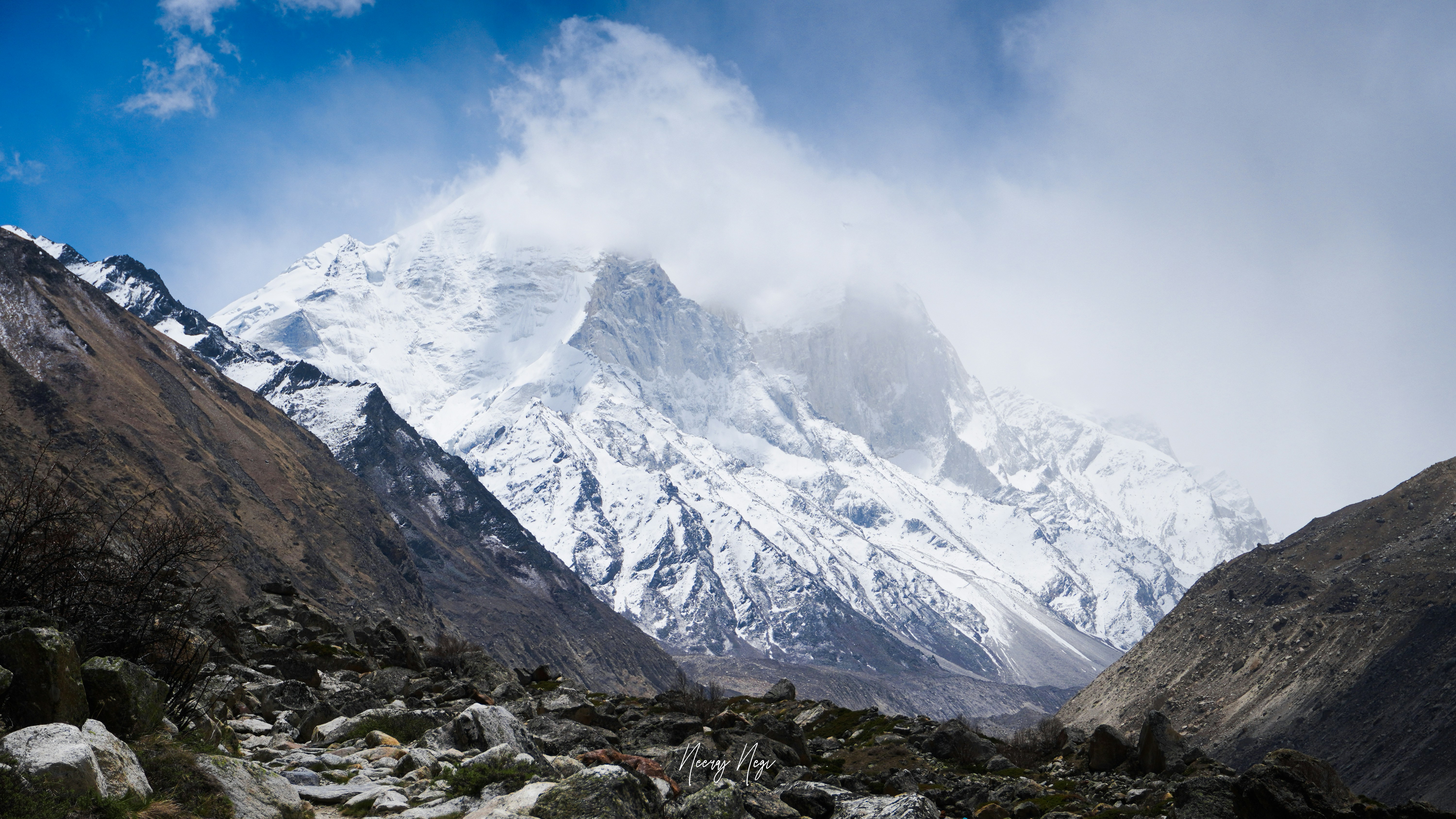 a mountain covered in snow and rocks under a cloudy sky