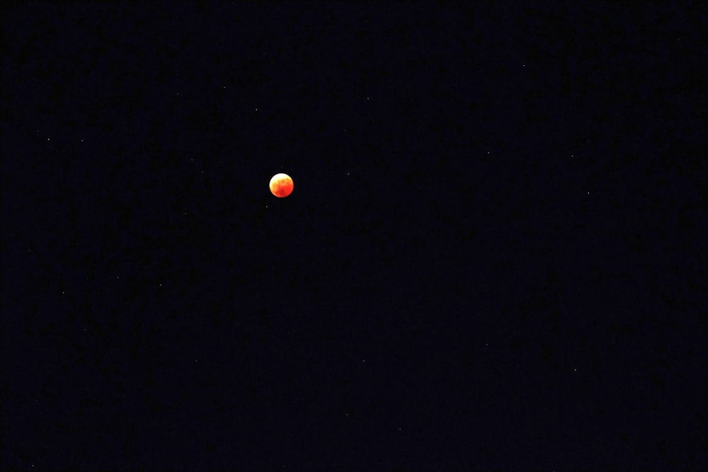 a red ball is seen in the dark sky