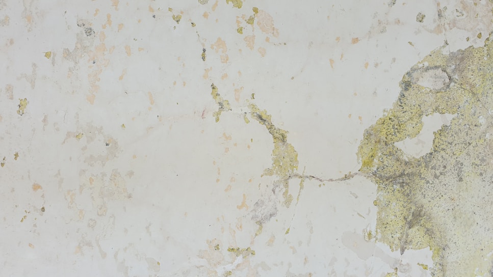 Close-up of weathered exterior wall showing peeling paint and surface cracks before renovation.