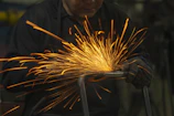 Welding sparks flying as a technician repairs a loader bucket attachment.