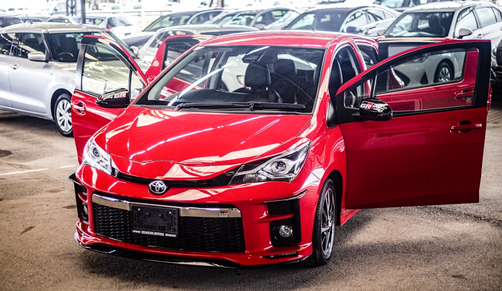 a red car parked in a parking lot next to other cars