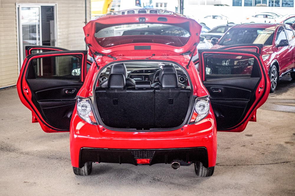 a red car with its hood open in a parking lot