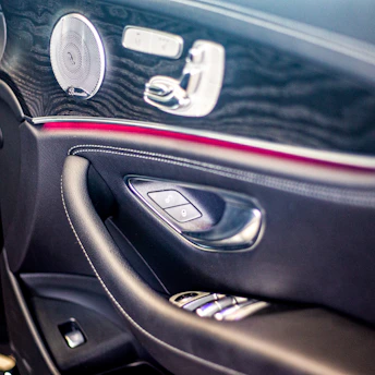 Close-up of a luxury car door panel featuring newly installed high-end speakers with sleek black and blue accents.